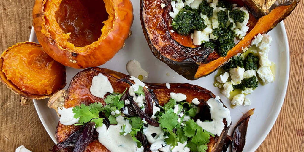 Three baked pumpkins on a plate with toppings