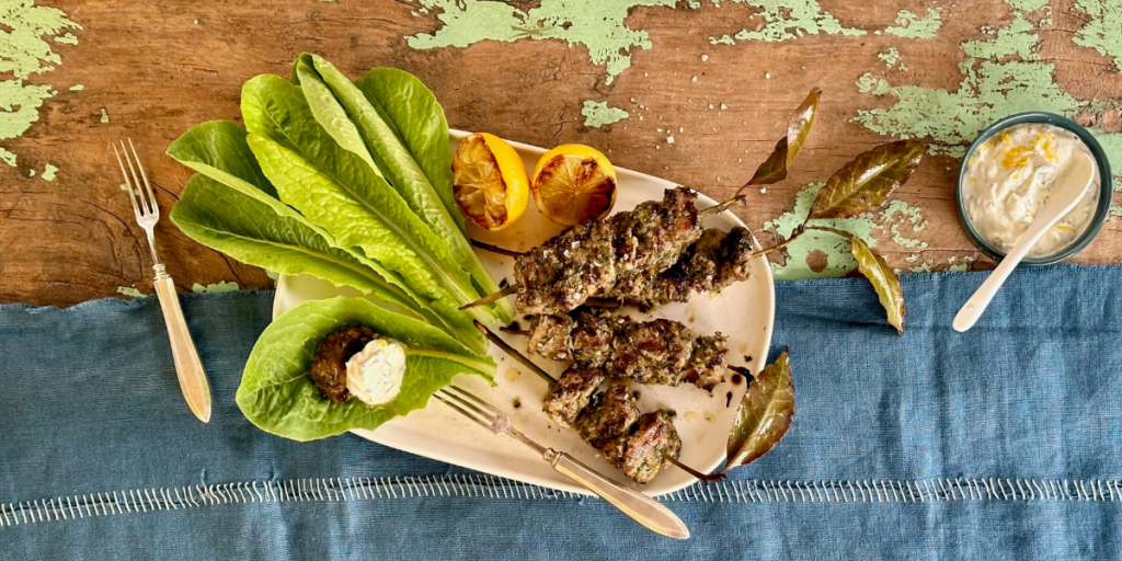 Lamb skewers on a plate with herb sauce.