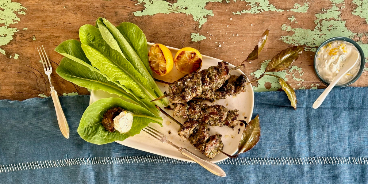 Lamb skewers on a plate with herb sauce.